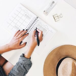 person holding ballpoint pen writing on white paper